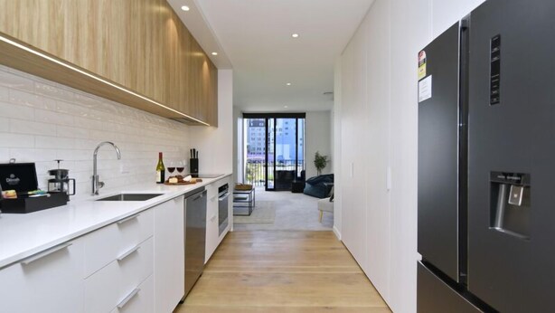 Eine moderne Küche mit weißen Schränken, einem Edelstahlkühlschrank und einer Essecke mit Sofa und Tisch.