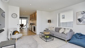 Ein modernes Wohnzimmer mit grauem Sofa, einem Couchtisch und einem Essbereich mit Tisch und Stühlen.