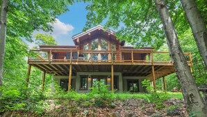 A wooden cabin with a balcony, surrounded by trees and foliage. - 7BR LogCabin/Spa/Nature/MontTremblant Area/18 Guests  (Labelle)