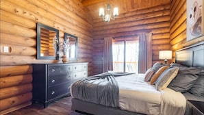 A log cabin bedroom with a bed, dresser, and chandelier. - 7BR LogCabin/Spa/Nature/MontTremblant Area/18 Guests  (Labelle)