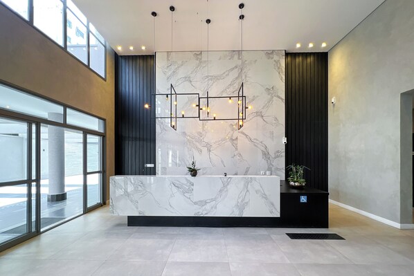 A modern reception area with a marble counter, pendant lighting, and large windows.
