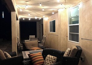 Un espace extérieur aménagé en terrasse, avec des meubles en osier et des guirlandes lumineuses.