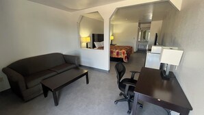 Ein Hotelzimmer mit Sofa, Schreibtisch, Stuhl, Bett und Spiegel.
