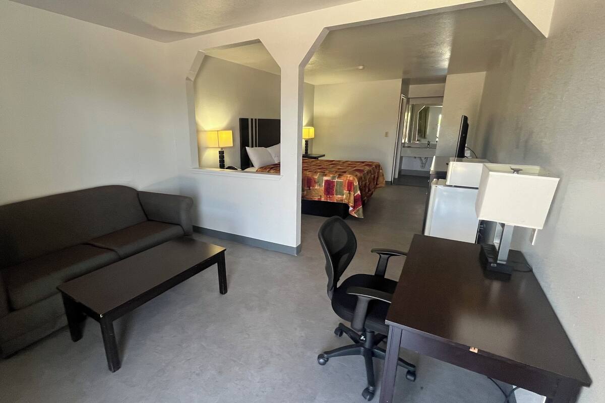 Une chambre d’hôtel équipée d’un canapé, d’un bureau, d’une chaise, d’un lit et d’un miroir.
