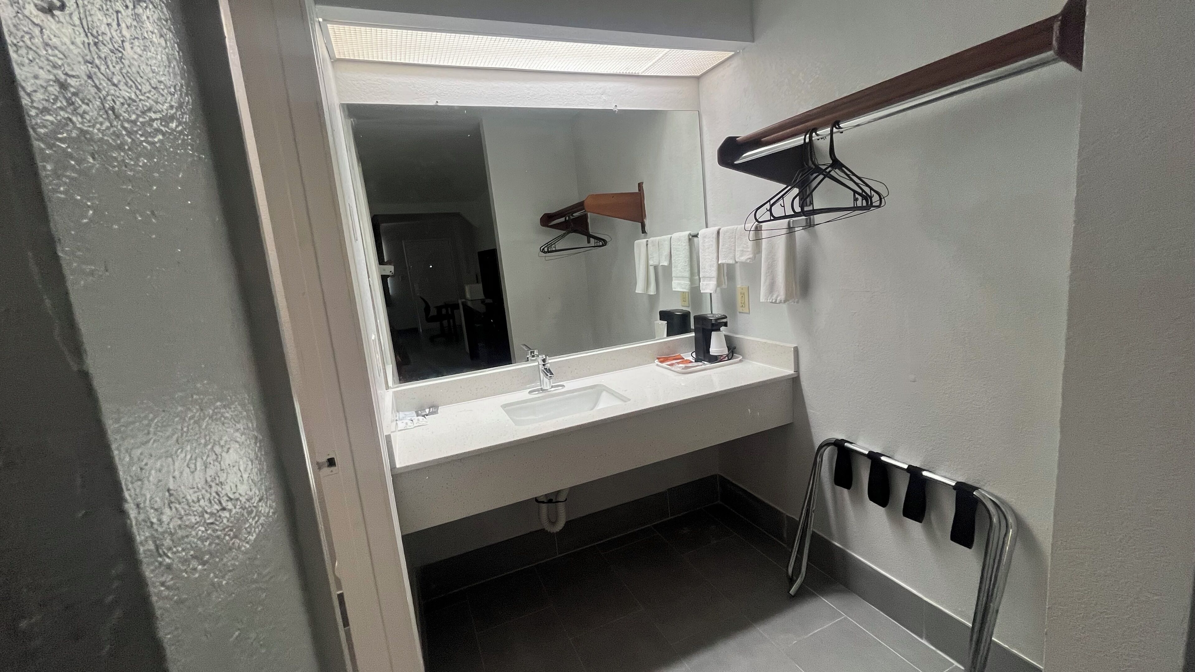 A bathroom with a white sink, a mirror, a towel rack, and a towel dispenser.