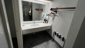 Ein modernes Badezimmer mit Waschbecken, großem Spiegel und Handtuchhalter.
