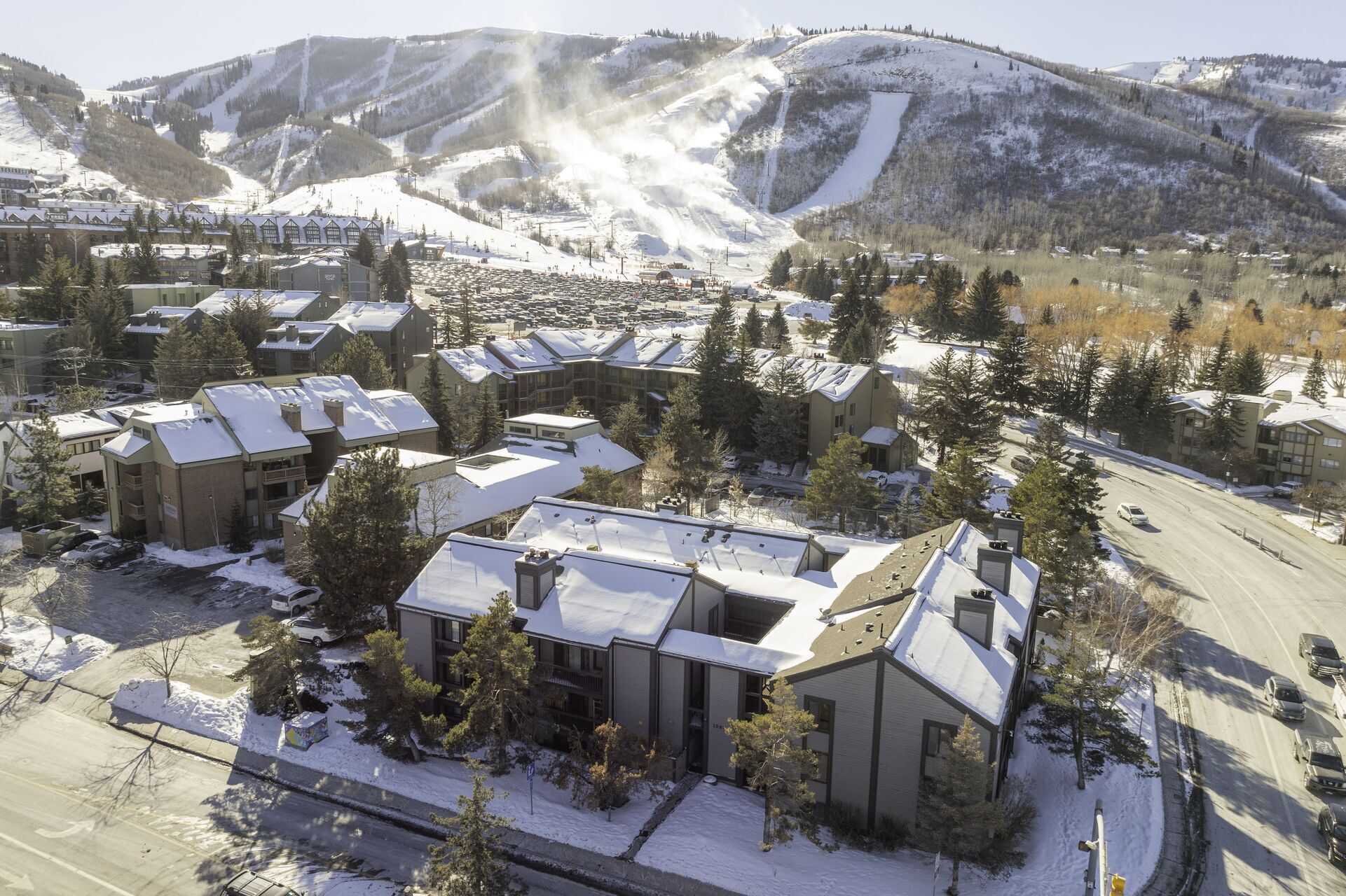 Un conjunto de edificios cubiertos de nieve, con varias construcciones, rodeado de árboles y una carretera.