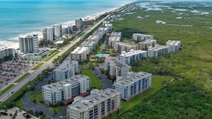 Luchtbeeld van een kustgebied met woonwijken, hoge gebouwen, een strand en een moerachtig landschap.