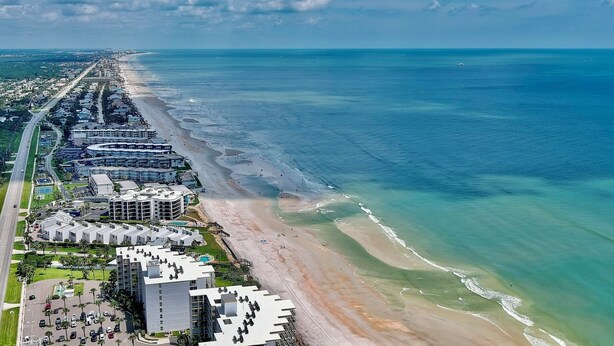 Een kusthotel met meerdere gebouwen, een strand en helder uitzicht op de oceaan.