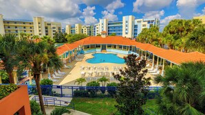 Een resort met een centraal gelegen zwembad, omringd door ligbedden en palmbomen.