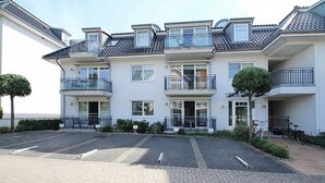 Ein mehrstöckiges Wohngebäude mit Balkonen, einer gepflasterten Auffahrt und einem Fahrrad davor.