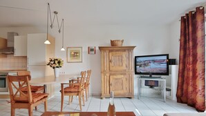 Ein modernes Wohnzimmer mit Fernseher, Holzmöbeln und einem Essbereich.