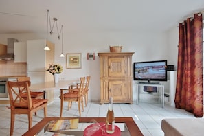 Un salon moderne avec un téléviseur, des meubles en bois et un coin repas.