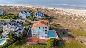 A beachfront property with multiple houses, a swimming pool, and a beach view.