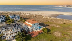 A coastal property with a large house featuring a pool, a beach, and a view of the ocean. - Hobbs Realty - Very Last Home on the Island w/Heated Pool, Elevator, Luxury Amenities (Holden Beach)