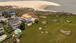 An aerial view of a coastal property with a large sandy beach, a swimming pool, and multiple buildings. - Hobbs Realty - Very Last Home on the Island w/Heated Pool, Elevator, Luxury Amenities (Holden Beach)
