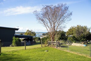 Um bairro residencial com um quintal cercado, uma árvore e vista para o mar.