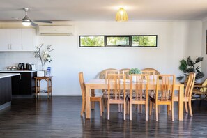 A modern kitchen with a dining area, wooden furniture, and a view through a window.