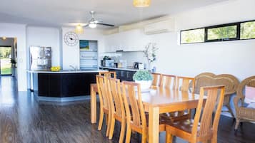 A modern kitchen with a central island, dining area with wooden chairs, and a large window providing natural light.