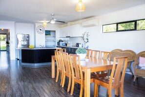 Cozinha moderna com ilha central, área de refeições com cadeiras de madeira e uma janela grande que proporciona iluminação natural.