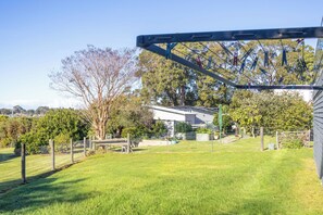 A residential property with a fenced yard, a house, and a large tree. - Bella Views Pet friendly with expansive views. (Mallacoota)