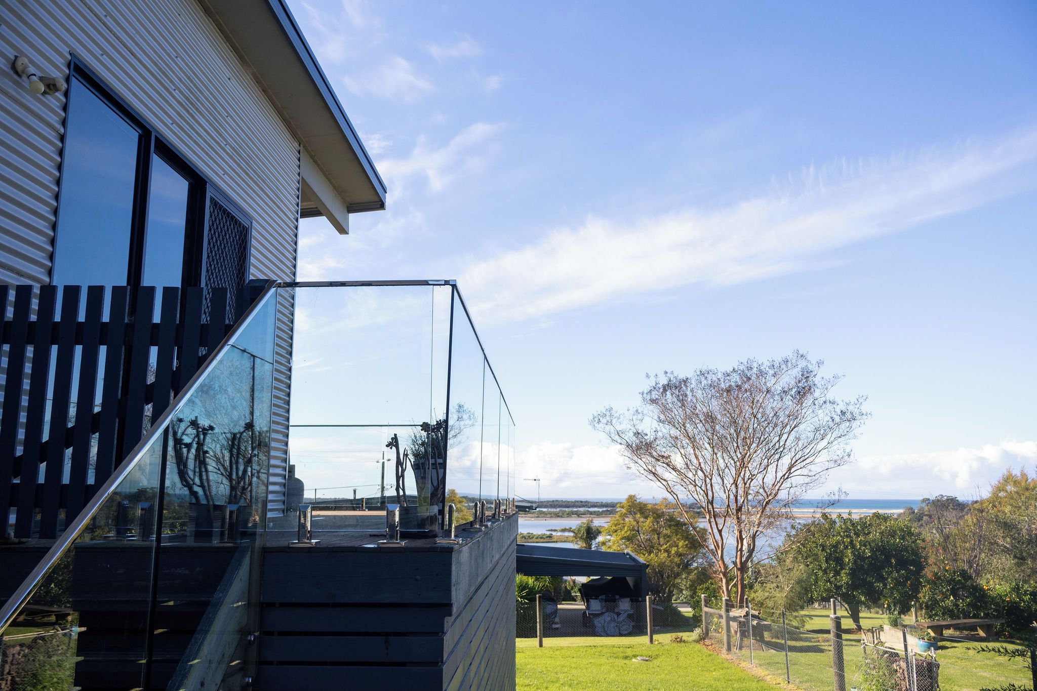 Una casa moderna con un balcone in vetro che si affaccia su un paesaggio naturale.
