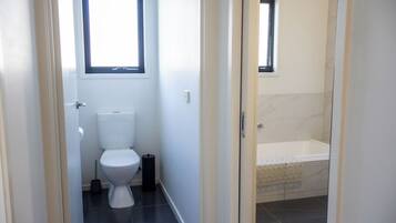 A bathroom with a toilet, a bidet, and a bathtub.