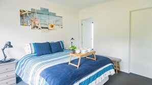 A bedroom with a bed, bedside table, lamp, and a small stool. - Bella Views Pet friendly with expansive views. (Mallacoota)