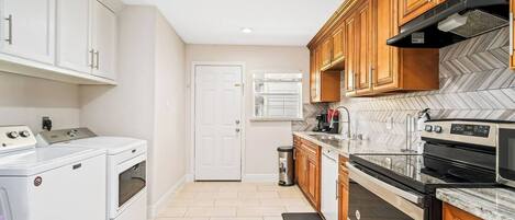 A kitchen with white appliances, wooden cabinets, and a herringbone tile backsplash.