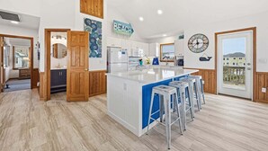 Une cuisine moderne dotée d’un îlot central, de touches de bois et offrant une vue sur l’extérieur.