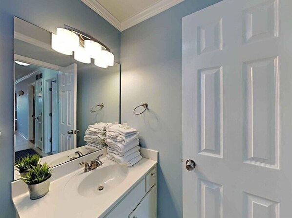 A bathroom with a white sink, a mirror, and a towel rack. - Emerald Coast Destin, St Martin Beachwalk Villas 121 (Destin)