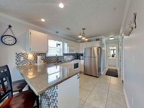 A modern kitchen with white cabinets, a stainless steel refrigerator, and a tiled backsplash.