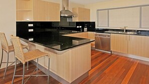 Enjoy cooking in this well-equipped kitchen with a central island, light wood cabinetry, and a stainless steel range hood.