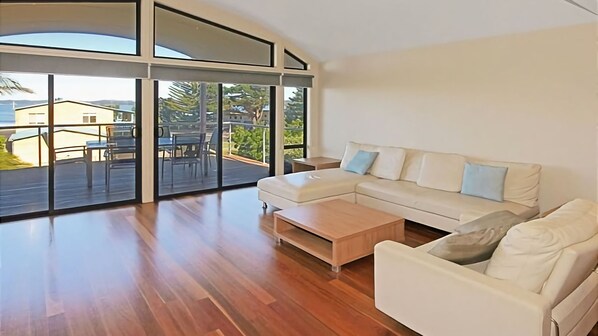 Relax in this spacious living room with a sofa, coffee table, and glass door leading to an outdoor patio.