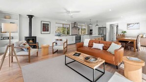 A modern living room with a sofa, coffee table, and a fireplace. - Kurrajong at Malua (Malua Bay)