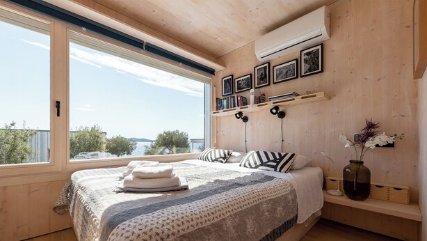 Une chambre avec un grand lit, une vue sur la mer et des murs en bois.