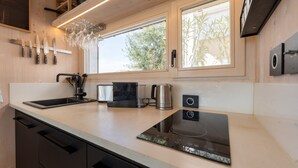 Une cuisine moderne équipée d’une cuisinière intégrée, d’un évier et d’une fenêtre donnant sur un espace verdoyant.