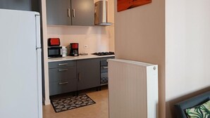 A compact kitchen with grey cabinets, a microwave, a coffee maker, and a gas stove.