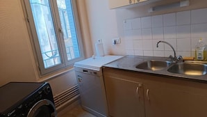 A compact kitchen with a built-in dishwasher, a sink, and cabinets.