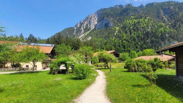 A rural village with traditional houses, a dirt path, and a mountain backdrop. - Luxury design chalet category 1, 105sqm, 2 separate bedrooms, Swiss stone pine furniture (Ruhpolding)
