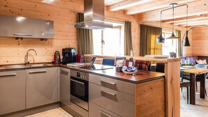A modern kitchen with stainless steel appliances, wooden cabinetry, and a central island. - Luxury design chalet category 1, 105sqm, 2 separate bedrooms, Swiss stone pine furniture (Ruhpolding)
