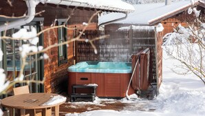 En træhytte med jacuzzi og en træterrasse.