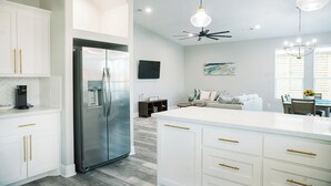 Una cocina moderna con refrigerador de acero inoxidable, armarios blancos y una isla central.