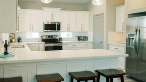 Una cocina moderna con armarios blancos, electrodomésticos de acero inoxidable y una isla grande con taburetes.