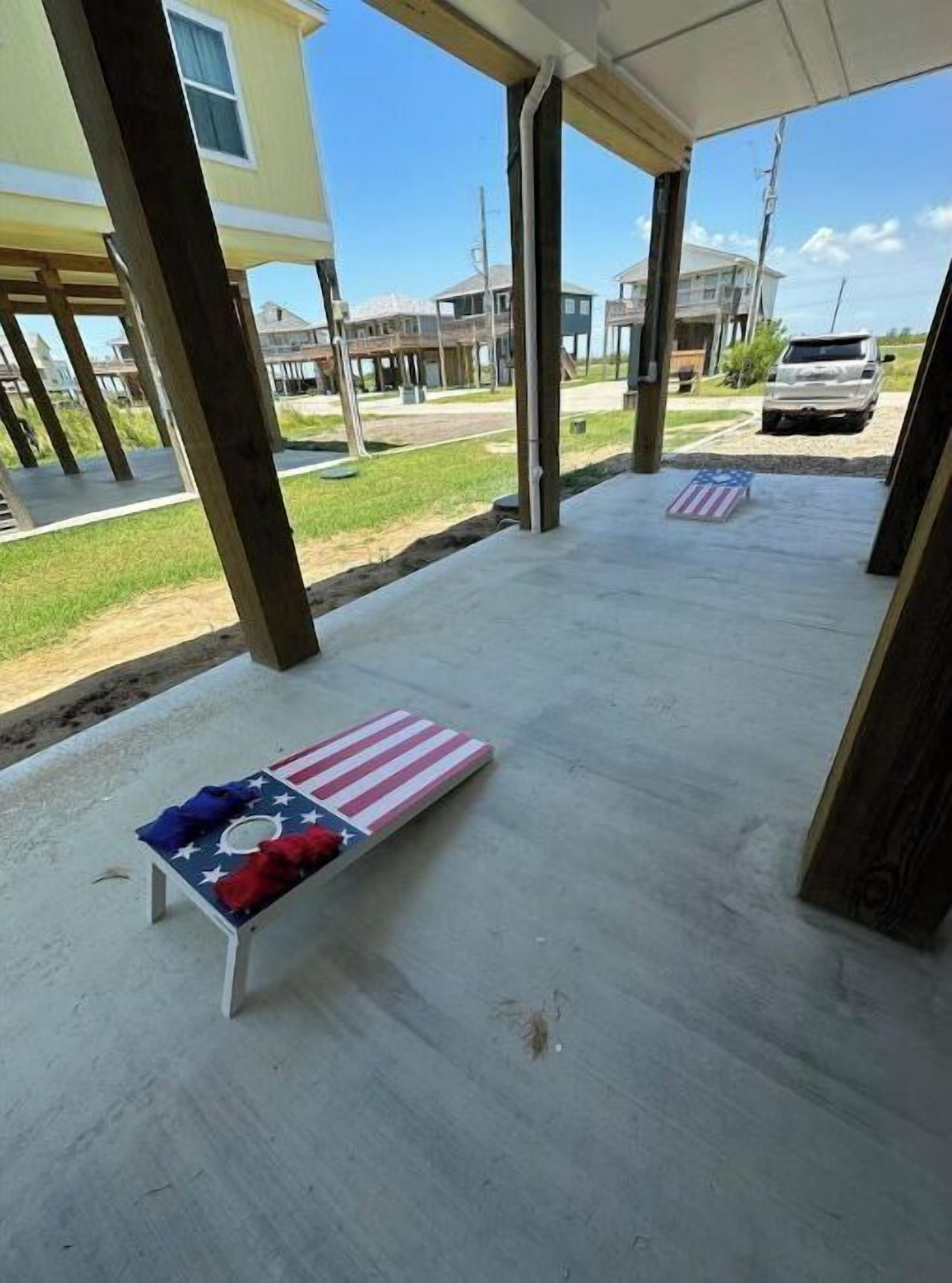 Et overdækket udendørs område med beton gulv og to lounge stole med amerikanske flag.