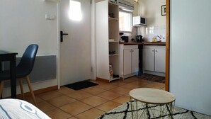 Un espacio habitable compacto con kitchenette, comedor y una pequeña zona de estar.