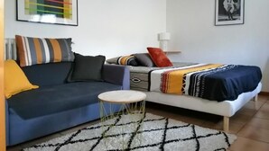 Una sala moderna con un sofá azul, un sofá blanco, una mesita redonda y un tapete estampado.