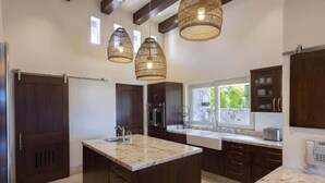 Une cuisine moderne avec des meubles en bois foncé, un plan de travail en marbre et des luminaires suspendus.