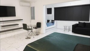 Ein modernes Zimmer mit Flachbildfernseher, einer Couch, einem kleinen Tisch und einem Sessel.