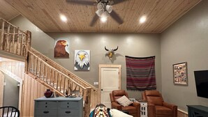 Un salon spacieux avec un escalier en bois, un canapé en cuir et un coin repas comprenant une table et des chaises.